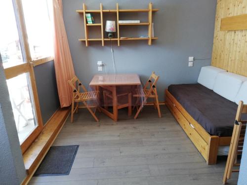 a room with a bed and a table and chairs at Studio 1 pièce PLAGNE VILLAGE 4 personnes 2050 M PIED DES PISTES in Plagne Villages