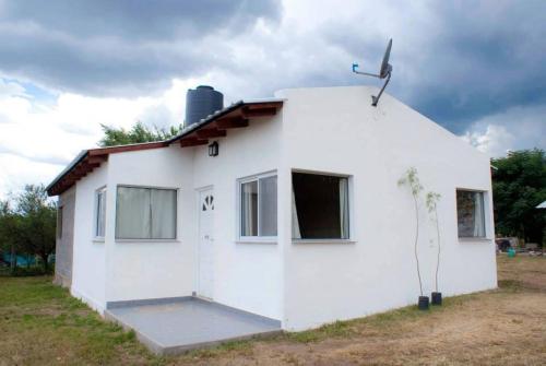 ein kleines weißes Haus mit Sat-TV in der Unterkunft Cabañas Luz de Luna, Comuna San Roque-Punilla in Cordoba
