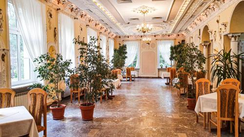 a dining room with tables and chairs and plants at Dworek Brodowo Restauracja Hotel Przyjęcia in Brodowo