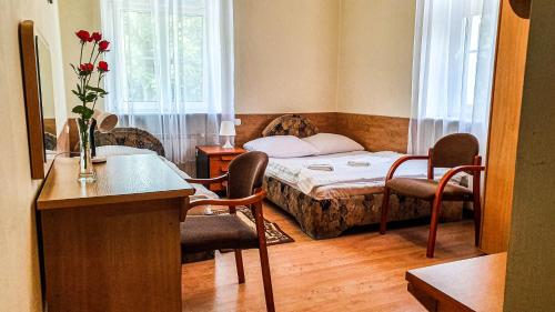 a small room with a bed and a table and chairs at Dworek Brodowo Restauracja Hotel Przyjęcia in Brodowo