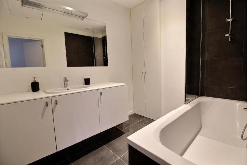 Rent a flat - Montgomery في بروكسل: حمام مع حوض أبيض ومغسلة وحوض استحمام
