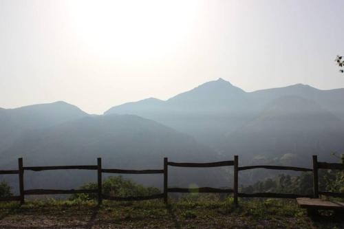 a fence on a hill with mountains in the background at Los Pradones in San Roque de Ríomiera