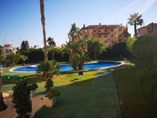 a resort with two swimming pools and palm trees at Alta Vista - apartamento con 2 dormitorios y vista al mar in Torrevieja