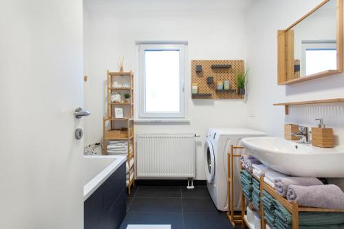 a bathroom with a sink and a mirror and a washing machine at Alpine Home Apartment in Bohinj