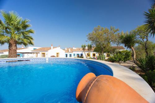 a swimming pool in front of a house with palm trees at Casas da Capela do Monte, Country Houses in Lagos