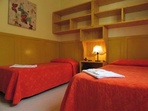 a room with two beds with red sheets and a lamp at Albergo Ristorante La Rocca in Firenzuola