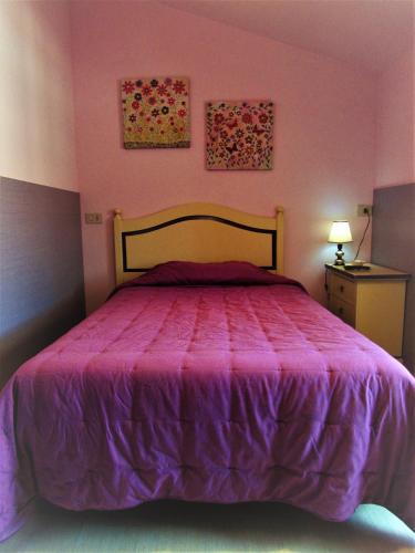 a pink bedroom with a bed with a purple bedspread at Albergo Ristorante La Rocca in Firenzuola