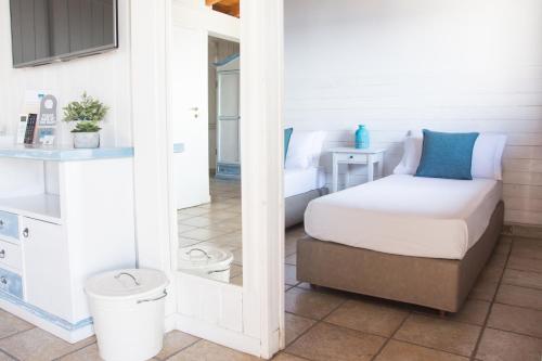 a small bedroom with a bed and a mirror at Hotel Corallo in Santa Maria al Bagno