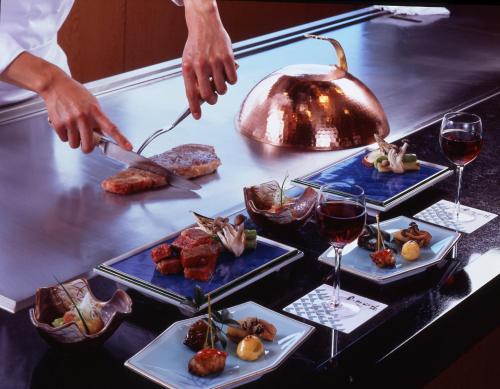 a table with three trays of food and glasses of wine at Keio Plaza Hotel Hachioji in Hachioji