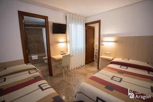 a hotel room with two beds and a bathroom at Hostal Aragón in Teruel