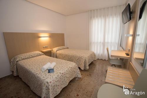 a hotel room with two beds and a desk at Hostal Aragón in Teruel