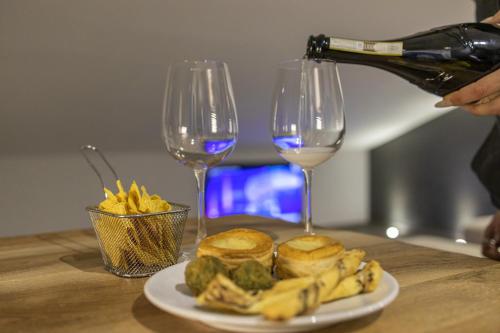 a person pouring wine into two wine glasses and a plate of food at Panoramic penthouse in the historical center in Domodossola