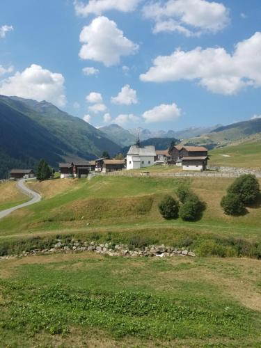 a green field with a white house on a hill at Tgèsa Felici in Sedrun