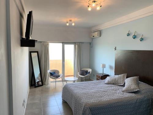 1 dormitorio con 1 cama, 2 sillas y ventana en Loft N1 con vista al mar en Las Grutas