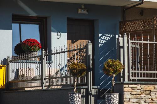 a blue house with a white fence and two potted plants at Posterunek Mariańska 9 in Polanica-Zdrój