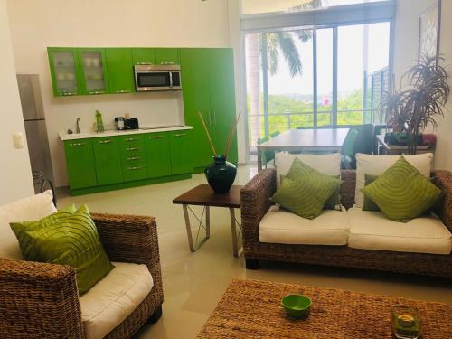 a living room with two chairs and a table and green cabinets at PuntaGaviota in Santa Cruz Huatulco