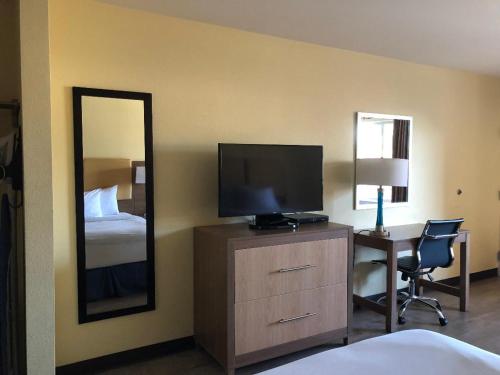 a hotel room with a television and a desk with a bed at Days Inn by Wyndham Hayward Airport in Hayward
