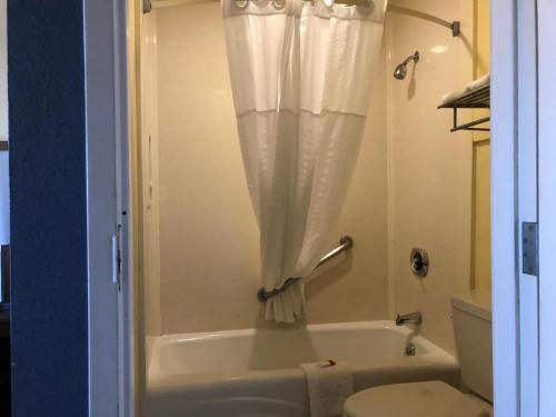 a bathroom with a tub and a toilet and a shower curtain at Days Inn by Wyndham Hayward Airport in Hayward
