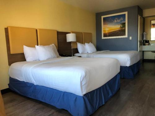 two beds in a hotel room with two at Days Inn by Wyndham Hayward Airport in Hayward