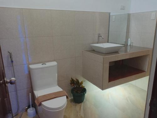 La salle de bains est pourvue de toilettes blanches et d'un lavabo. dans l'établissement Chez Melanie Valencia Dumaguete GetAway, à Valencia