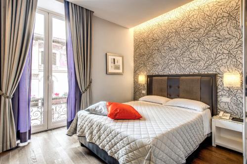 a bedroom with a bed with a red pillow on it at Roma Boutique Hotel in Rome