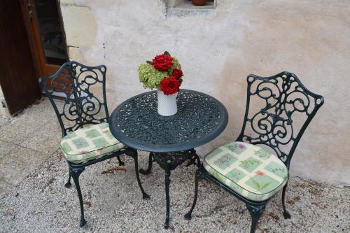 2 Stühle und ein Tisch mit einer Blumenvase in der Unterkunft Le Moulin de Lusseau in Chef-Boutonne