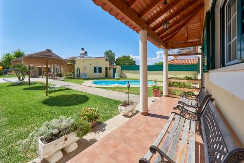 un patio avec deux bancs et une piscine dans l'établissement Quinta dos Pastores, à Estanqueiro