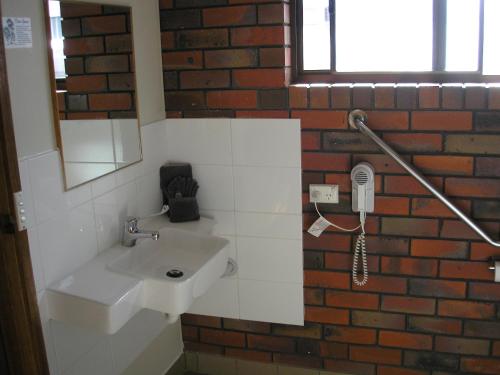 a bathroom with a white sink and a brick wall at Coorrabin Motor Inn in Stawell