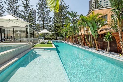 a swimming pool with trees and a building at Ultra Broadbeach in Gold Coast