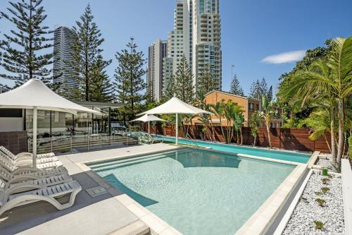 
a beach with a pool, chairs, and a balcony at Ultra Broadbeach in Gold Coast
