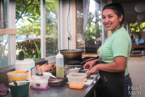 a woman standing in a kitchen preparing food at Hotel M&M Beach House in Coco