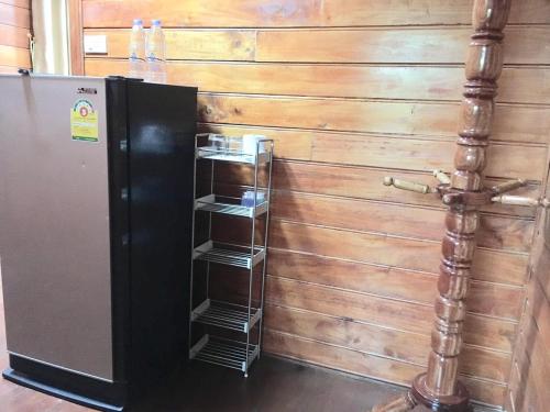 a black refrigerator with three shelves next to a wooden wall at Life and Love house in Ban Na Noi