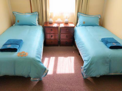 two beds in a room with blue walls at Twelve Apostles Motel & Country Retreat in Princetown