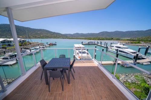a balcony with a table and chairs and a marina at Harbour Cove in Airlie Beach