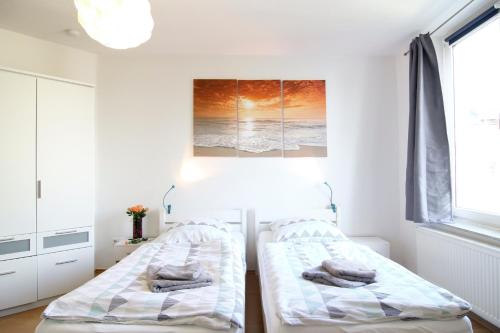 two beds in a white room with a picture on the wall at apartmondo Apartmentwohnungen Remscheid in Remscheid