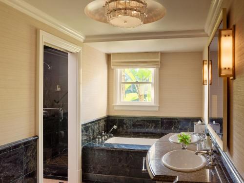 
a bathroom with a tub, sink, and mirror at The Beverly Hills Hotel - Dorchester Collection in Los Angeles
