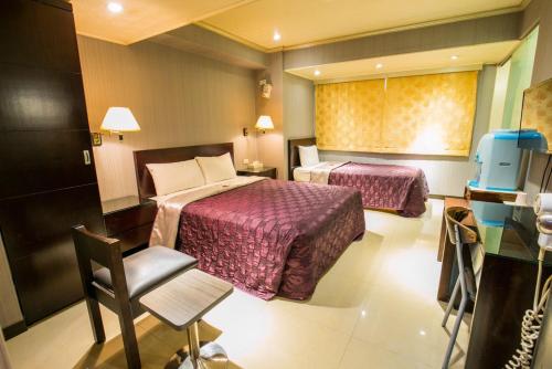 una camera d'albergo con due letti e una sedia di Pai Yueh Hotel a Taipei
