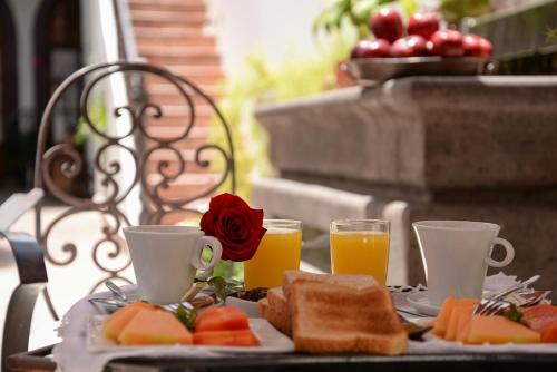 a table with a plate of food and two cups of orange juice at El Serafin Hotel Boutique in Querétaro