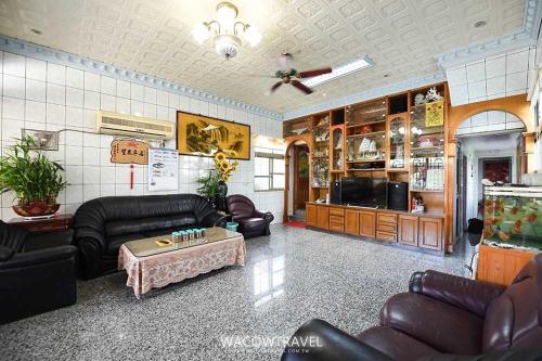 a living room with leather couches and a table at Mom Pan Bed and Breakfast in Xiaoliuqiu