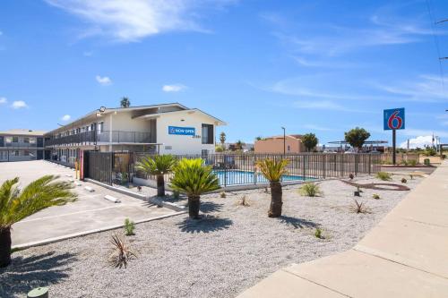 a parking lot with palm trees in front of a building at Motel 6-Moreno Valley, CA - Perris in Moreno Valley