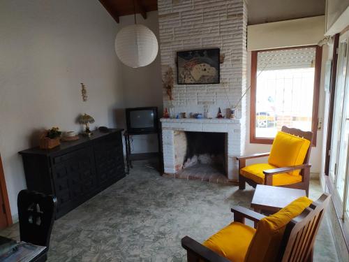 sala de estar con chimenea y silla amarilla en Chalet Ymaz en Villa Gesell