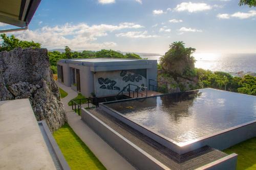 a house with a swimming pool in front of the ocean at Hanalee Villa Kouri in Nakijin