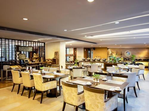 a restaurant with tables and chairs in a room at Jambuluwuk Malioboro Hotel Yogyakarta in Yogyakarta
