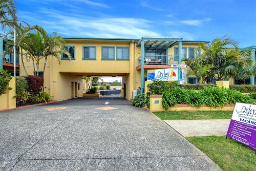 a large yellow building with a driveway at Oxley Cove Holiday Apartment in Port Macquarie