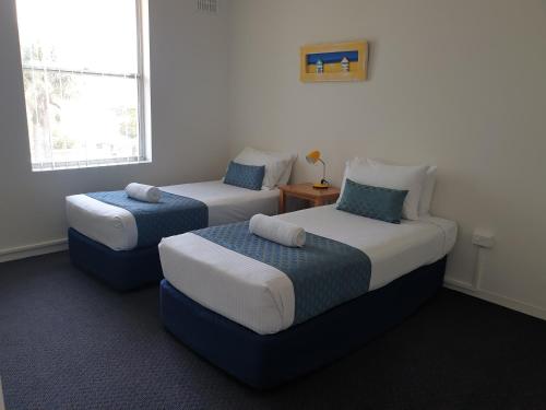 a bedroom with two beds and a table and a window at Oxley Cove Holiday Apartment in Port Macquarie