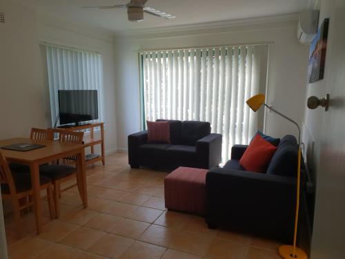 a living room with a couch and a table at Oxley Cove Holiday Apartment in Port Macquarie