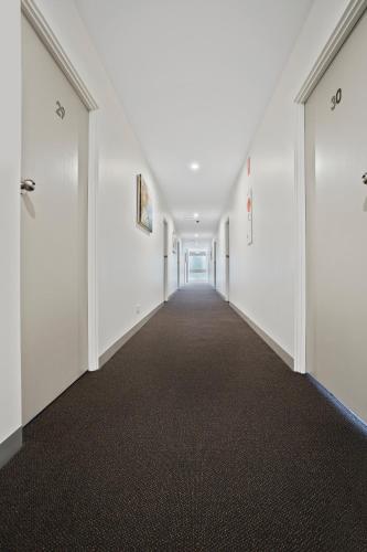 an empty corridor with white walls and a long hallway at Parkside Motel Geelong in Geelong