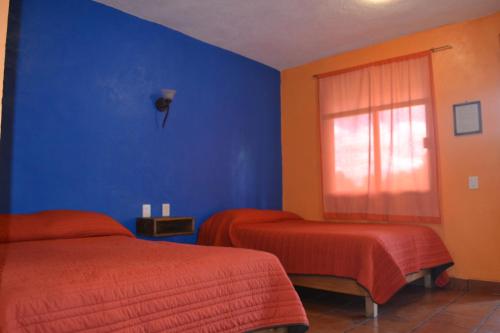 1 dormitorio azul con 2 camas y ventana en Hotel Quetzalcalli, en San Juan Teotihuacán
