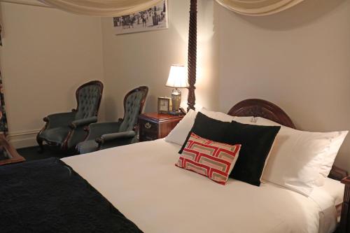 a bedroom with a white bed with two chairs at Yarra Valley Grand in Yarra Glen