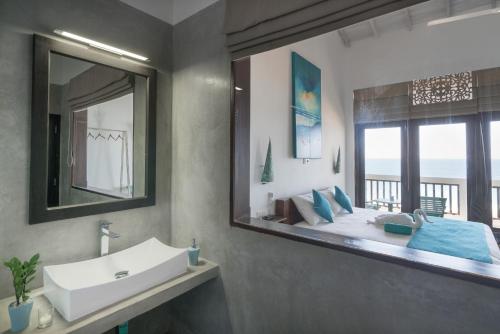 un bagno con lavandino, specchio e letto di At Ease Beach Hotel a Hikkaduwa